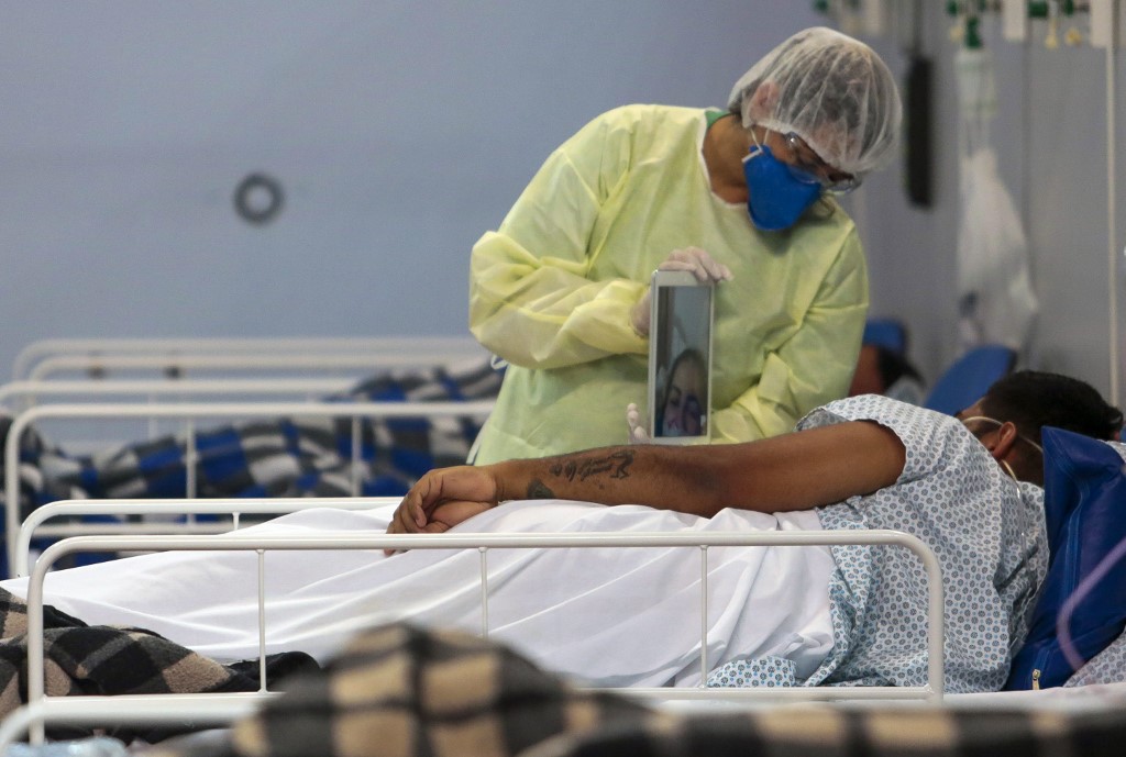 A patient affected by the COVID-19 Coronavirus speaks with a family member by a video call at a field hospital set up at a sports gym, in Santo Andre, Sao Paulo state, Brazil, on May 11, 2020. By Miguel Schincariol / AFP. 